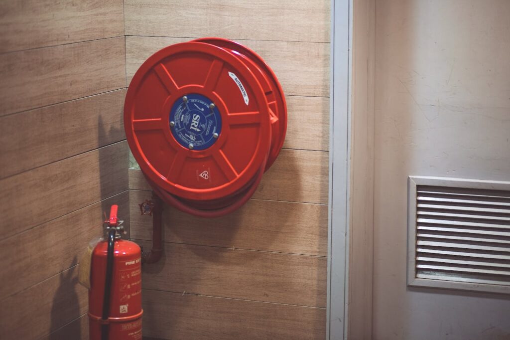 pexels-photo-189474 Red fire hose reel and extinguisher inside a building corner.
